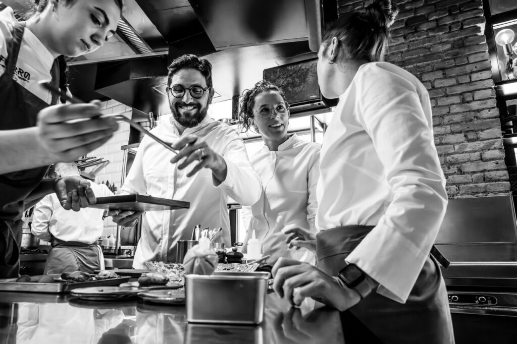 Equipo de cocina del restaurante Fierro trabajando en un servicio, emplatando con diferentes mujeres del equipo.