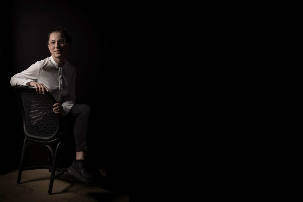 La chef del restaurante Fierro Carito Lourenço sentada en una silla sobre fondo negro.